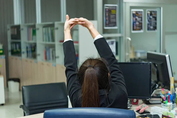 Asian officer woman stretching body at the desk of office from back angle,Thailand people,Businesswoman tired from hard work