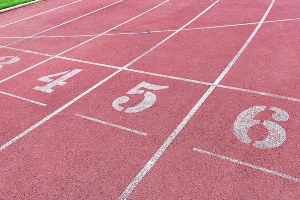 White Number six,five,four  athletic track number on red rubber racetrack, texture of running racetracks in stadium