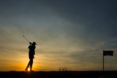 Siluet Asyalı golfçü güzel günbatımında golf oynuyor