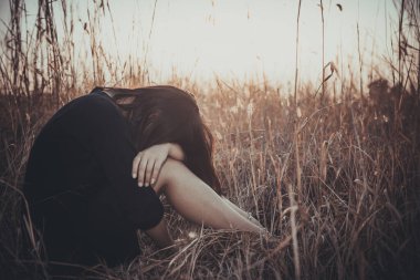 Tarlada yapayalnız bir kadının portresi. Klasik filtre stili. Aşktan kalbi kırık, günbatımı tarzında üzgün kız konsepti.