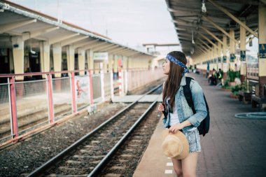 Asyalı turist tren istasyonunda bekliyor. Taylandlı hippi kadın seyahate çıkıyor.