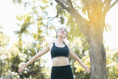Sıska bir kadının parkta temiz hava hisseden portresi, parlak güneş ışığı, insanların yaşam tarzı sağlığa, Asyalı kadın koşusuna, Tayland 'a ve