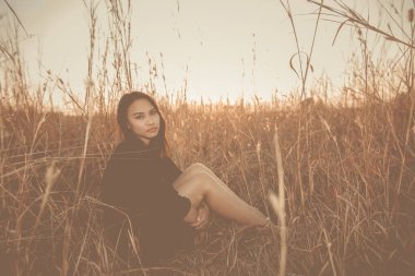 Tarlada yapayalnız bir kadının portresi. Klasik filtre stili. Aşktan kalbi kırık, günbatımı tarzında üzgün kız konsepti.