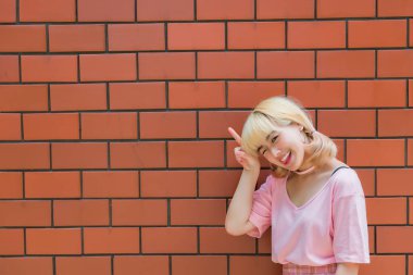 Taylandlı bir kadının portresi altın saçlar turuncu tuğla duvarda Japon tarzı, Asyalı bir kız açık havada fotoğraf çektirmek için poz veriyor.
