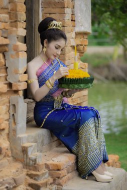 Tayland elbisesi içindeki güzel Asyalı kadın portresi geleneksel dua Kratong 'u, Tayland' da düzenlenen loy kratong festivaline katılması için tutuyor.