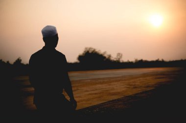 Siluet Genç Asyalı Müslüman adam gün batımında dua ediyor, Ramazan festivali konsepti