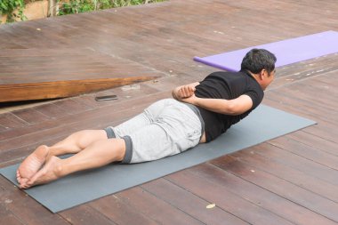 Genç adam yerde yoga yapıyor.