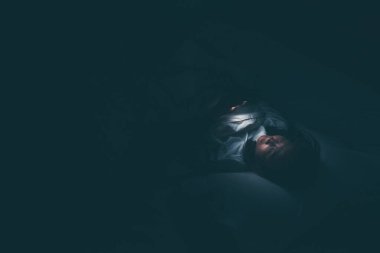 Asyalı kadın gece yatakta akıllı telefonla oyun oynuyor, Taylandlılar, sosyal medya bağımlısı.