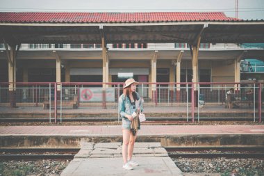 Asyalı turist tren istasyonunda bekliyor. Taylandlı hippi kadın seyahat ediyor. Elinde kamera var.