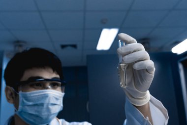 Bilim adamı deneyden önce kimyasalları sallama makinesiyle karıştırdı. Laboratuvarda çalışan Tayland 'lı bilim adamı test tüplerine numuneler karıştırdı.