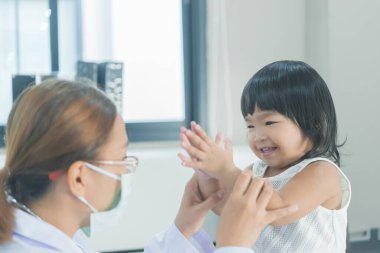 Solunumunu ve kalbini kontrol etmek için steteskop kullanan Asyalı bir doktor, Taylandlı çocukların sağlığını kontrol ediyor.