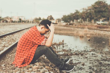 Yakışıklı bir adamın portresi üzgün Tayland demiryollarında oturur