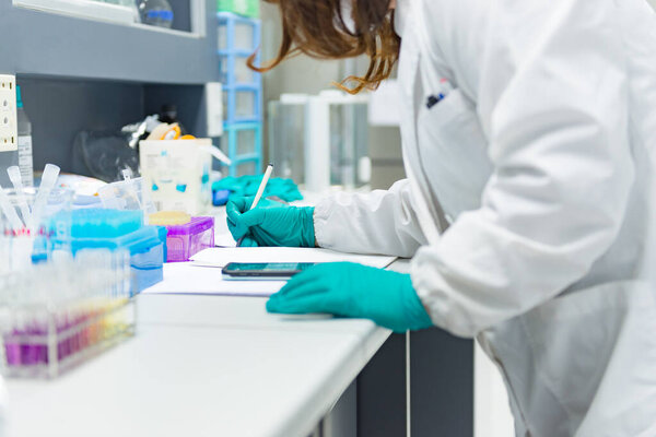 Scientist record the experiment of mix chemicals In the laboratory.Mixture laced with samples into test tubes.