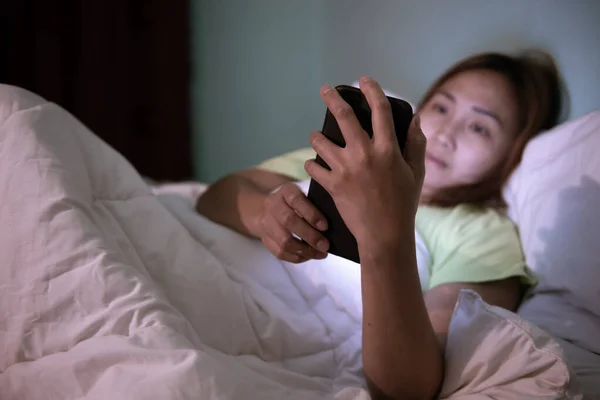 Asian woman play smartphone in the bed at night,Thailand people,Addict social media,Play internet all night,Lychnobite