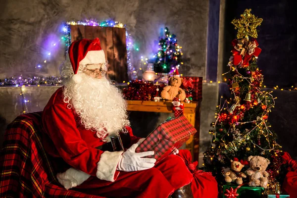 Santa claus holding gift box at home,Sit on chair think about plan for sent gift box for give children