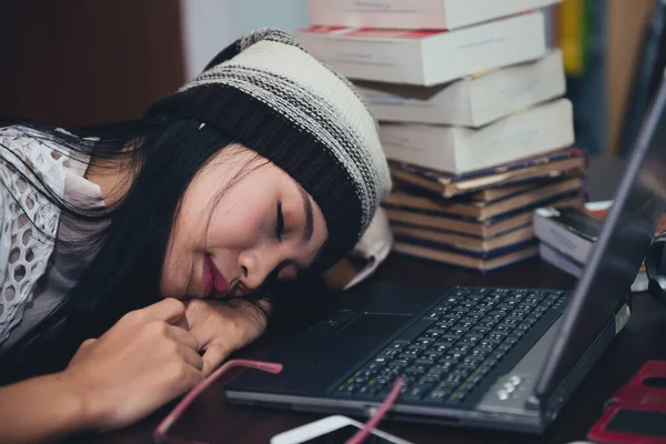 beautiful asian woman sleep on the desk with laptop in the library