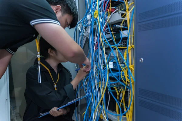 两名在服务器室工作的亚洲工程师 检查计算机网络的连接问题 泰国人 — 图库照片