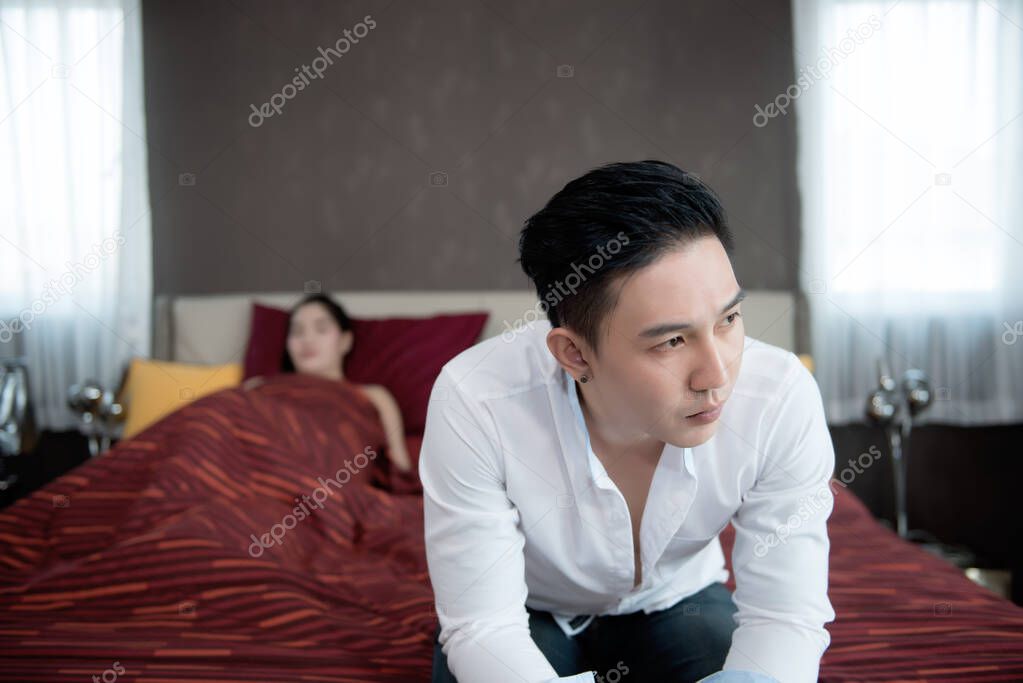 Handsome man serious after sex with a girl on the bed