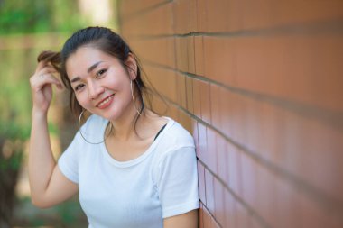 Güzel Asyalı şık kızın portresi tuğla duvarda fotoğraf çektirmek, gençlerin yaşam tarzı, modern kadın mutlu konsepti.