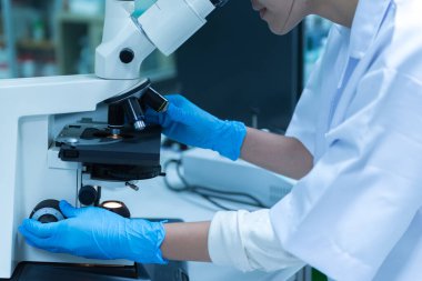 Genç Asyalı bilim adamı bir laboratuarda mikroskoptan bakıyor. Taylandlılar biraz araştırma yapıyor..