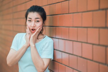 Güzel Asyalı şık kızın portresi tuğla duvarda fotoğraf çektirmek, gençlerin yaşam tarzı, modern kadın mutlu konsepti.