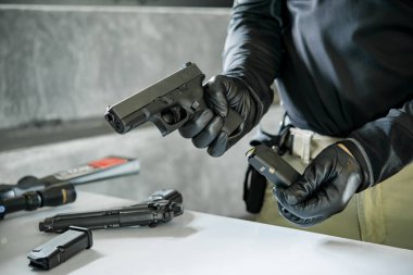 Elinde silahla siyah deri eldivenler giyen Asyalı bir erkek silaha kurşun dolduruyor.