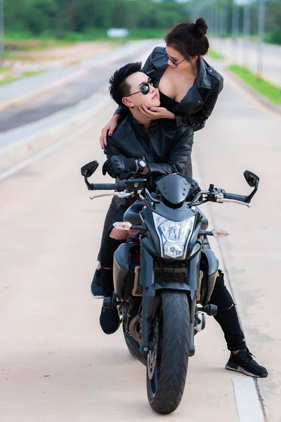 asian couple of bikers with motorcycle on road