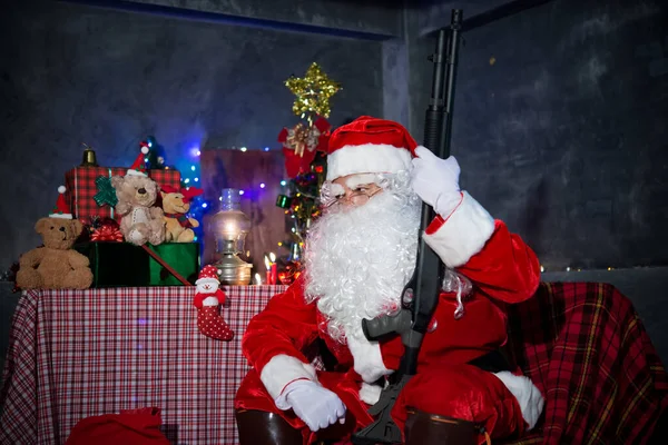 Angry Santa claus holding Shortgun at home,Sit on chair think about plan for sent gift box for give children