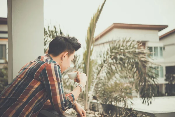 Handsome young man drinking coffee on the balcony, young modern, trendy,time for relax and rethink something of life,drink for fresh,vintage style,dark tone