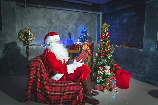 Santa claus holding gift box at home,Sit on chair think about plan for sent gift box for give children