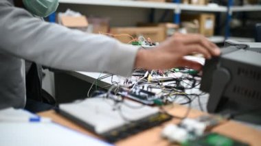 Koruma maskesindeki teknisyen depodaki stokları kontrol ediyor. Laboratuvardaki mühendislik ekipmanları sayıyor. 