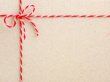 Kraft kağıt zemin üzerinde bir yay bağlı Noel dize, kırmızı sicim.