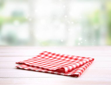 Ahşap masa boş alanı zemin üzerine katlanmış pötikareli kırmızı piknik kumaş damalı. Mutfak peçete.