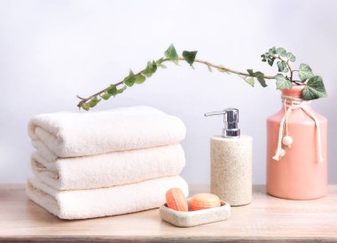 Banyo personeli, katlanmış havlu yığını ve soap üzerinde ahşap teble. Doğal vücut bakım ürünleri.