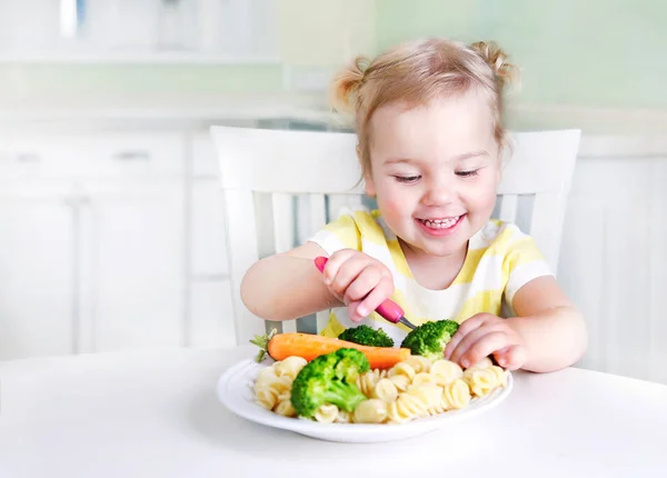 Barnflicka sitter vid bordet med en tallrik med mat, Kid äta vege Guest — Stockfoto