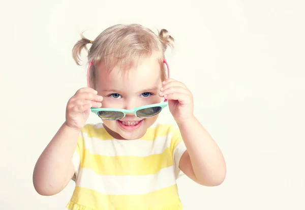 Barn ghirl bär solglasögon sommar gul bakgrund. — Stockfoto