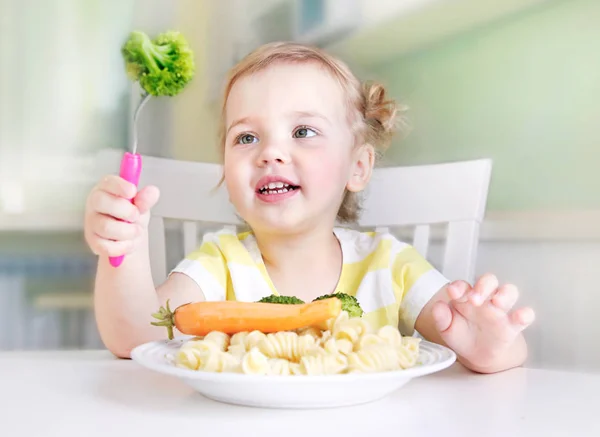 テーブルで健康的な食べ物を食べる小さな女の子. — ストック写真