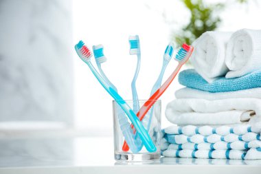 Diş fırçaları ve havlular banyoya istiflenir. Bardaktaki diş fırçası boş fotokopi sehpasına konur..