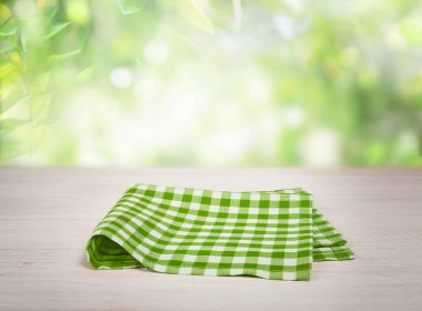 Piknik kareli yeşil katlanmış havlu bezi ahşap masa üzerinde boş alan bulanık doğal arkaplan.