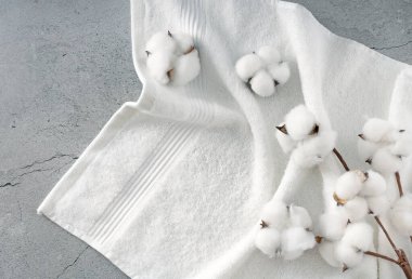 Pamuk çiçek tomurcukları ve dallarla süslenmiş beyaz havlu üst görünüm dokusu. Boş alan tuvaleti arka planı, ürün ekranı. Kozmetik reklam sınırı, çerçeve. Spa arkaplanı.,