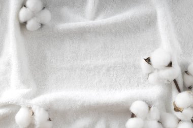 Pamuk çiçeği tomurcuğuyla dekore edilmiş beyaz havlu dokusu. Kozmetik arka planı, spa arka planı. Banyo ögeleri gösteriliyor. Boş kopya alanı çerçevesi.