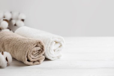 Masaj ve rahatlama arka planında. Terry havluları ahşap boş yere sarılmış. Banyo ürünleri sergileniyor. Hijyen ürünleri mockup.Dermatoloji ve kozmetoloji..