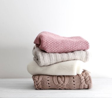 Bir yığın örgü kıyafet, katlanmış süveterler boş arka planda yığılıyor. Kış örgü öbek öbek öbek öbek masa örüyor, kimse örmüyor. El yapımı giysiler üst üste yığılıyor..