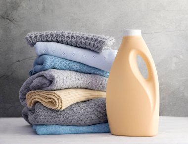 Yıkama jeli şişesi ve örgü giysileri, örgü ve yumuşatıcı. Yıkanmış giysiler. Ev konsepti..