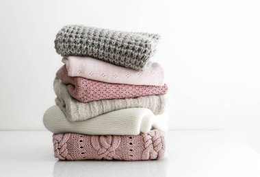 Yünlü örülmüş süveter yığını, sıcak kış sonbahar kıyafetleri beyaz masaya istiflenmiş. Kimse yok. Boş kopya alanı..