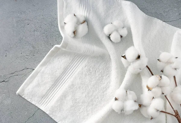Pamuk çiçek tomurcukları ve dallarla süslenmiş beyaz havlu üst görünüm dokusu. Boş alan tuvaleti arka planı, ürün ekranı. Kozmetik reklam sınırı, çerçeve. Spa arkaplanı.,