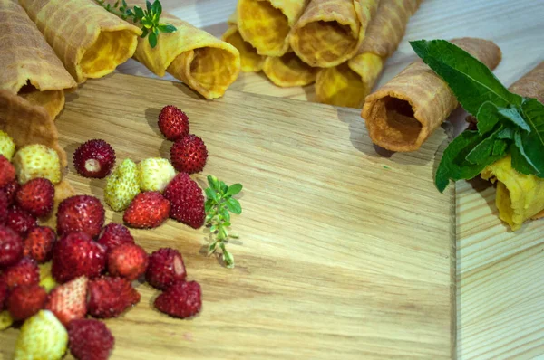 Waffle tüpleri, çay ya da kahve için çilek. Dekore edilmiş hafif ahşap bir arkaplanda kompozisyon. 