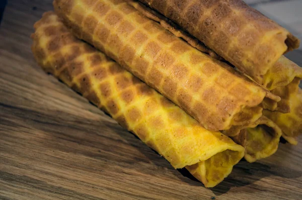 Waffle tüpleri, çay ya da kahve için çilek. Dekore edilmiş hafif ahşap bir arkaplanda kompozisyon. 