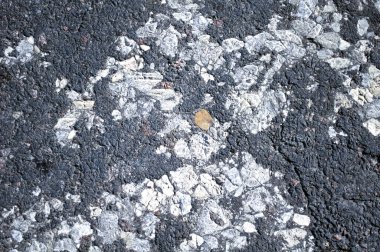 Yarı tahrip olmuş granüler asfalt, eski yol üretim teknolojisi. Kaldırımlar, yol kenarı, yakın plan.