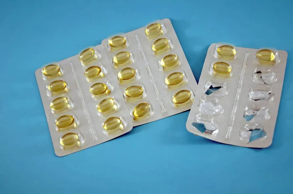 Blister of yellow pills, vitamins, tablet, medicine  on blue background